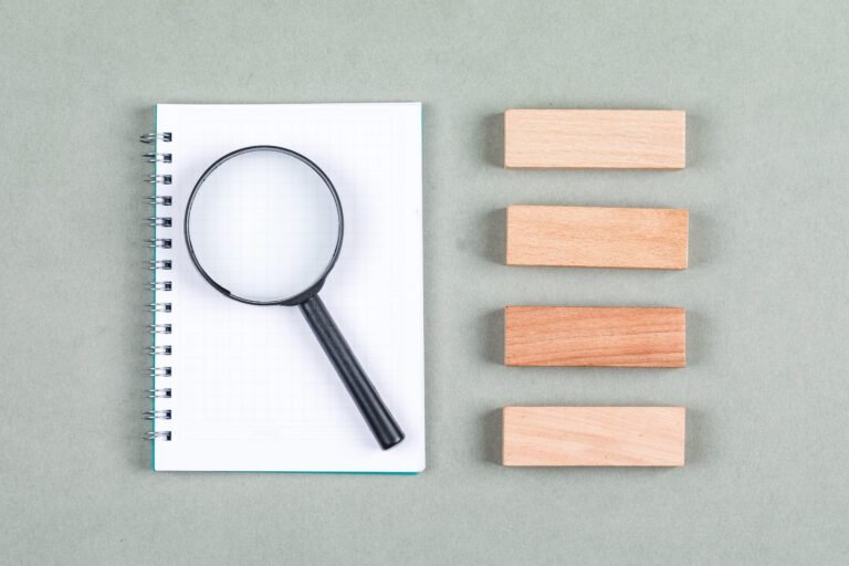 Searching and research concept with notebook, magnifier, wooden blocks on gray background top view